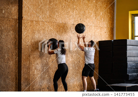 Two people training with medicine balls in a gym Two people training with medicine balls in a gym 141773455