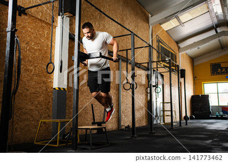 Athletic man doing dips at crossfit gym 141773462