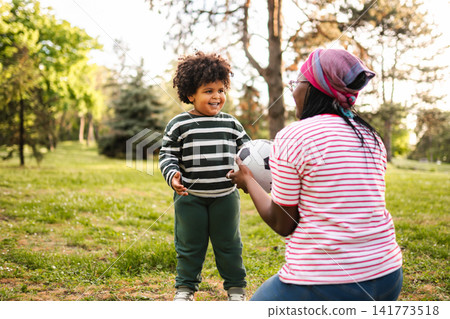 Mother and son playing soccer in park Mother and son playing soccer in park 141773518