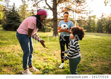 Family playing soccer in park during golden hour Family playing soccer in park during golden hour 141773519
