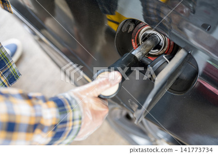 Close-up of driver refueling black car at gas station Close-up of driver refueling black car at gas station 141773734