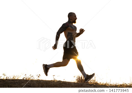 Running at sunset on a trail with silhouette of a man in athletic gear 141773945