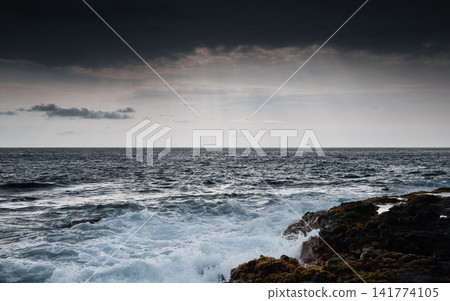 Stormy Ocean Waves Crashing on Rocky Coast Under Dark Sky Stormy Ocean Waves Crashing on Rocky Coast Under Dark Sky 141774105