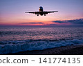 Passenger airliner landing over the ocean against the backdrop of scenic sunset sky 141774135