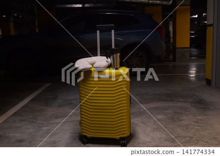 Relaxed Scene Featuring Luggage And Travel Comfort. Casual Travel Arrangement With Soft Cushion And City Backdrop. Calm Travel Moment With Luggage And Plush Neck Pillow In City Parking Area 141774334