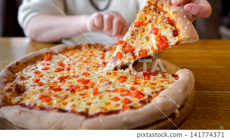 Hand Pulling Pizza Slice At Cafe, Hot Melted Cheese And Golden Crust On Rustic Wooden Table, Casual Dine Scene With Warm Sunlight, Inviting Aroma, Customer Grabbing Slice Taking Bite Hand Pulling Pizza Slice At Cafe, Hot Melted Cheese And Golden Crust On Rustic Wooden Table, Casual Dine Scene With Warm Sunlight, Inviting Aroma, Customer Grabbing Slice Taking Bite 141774371