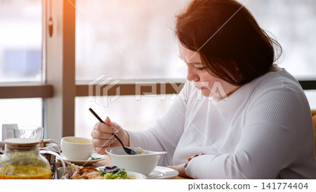 Woman Eats Peacefully. Serene Woman Dining Calmly. Quiet Scene Of Woman With Chopsticks. Tranquil Moment Of Woman Enjoying Meal By Window. Calm Scene Of Lady Relaxing With Steaming Bowl Near City View Woman Eats Peacefully. Serene Woman Dining Calmly. Quiet Scene Of Woman With Chopsticks. Tranquil Moment Of Woman Enjoying Meal By Window. Calm Scene Of Lady Relaxing With Steaming Bowl Near City View 141774404