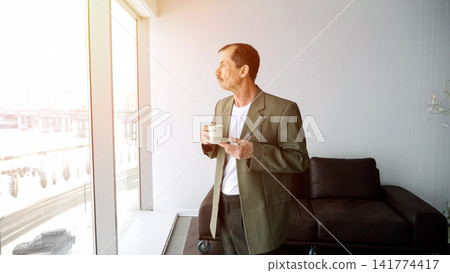 Person Peacefully Enjoys Sunrise With Coffee In Hand. Man Relaxes During Dawn With Warm Beverage In Hand. Individual Finds Tranquility In Morning Sunlight While Sipping Cup Of Coffee Calmly Person Peacefully Enjoys Sunrise With Coffee In Hand. Man Relaxes During Dawn With Warm Beverage In Hand. Individual Finds Tranquility In Morning Sunlight While Sipping Cup Of Coffee Calmly 141774417