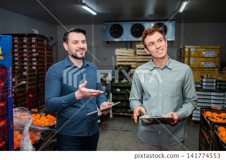 Warehouse managers analyzing inventory in produce cold storage Warehouse managers analyzing inventory in produce cold storage 141774553