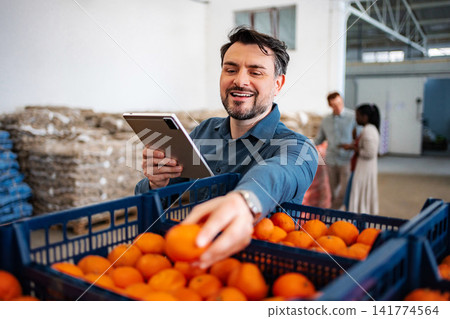 Man checking orange quality in warehouse with tablet Man checking orange quality in warehouse with tablet 141774564