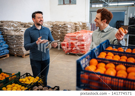 Two men are discussing fresh produce in a wholesale market warehouse Two men are discussing fresh produce in a wholesale market warehouse 141774571