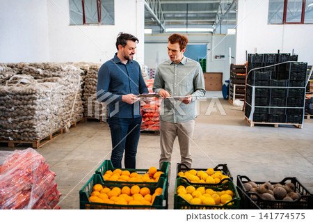 Two men discussing inventory in a fresh produce warehouse Two men discussing inventory in a fresh produce warehouse 141774575