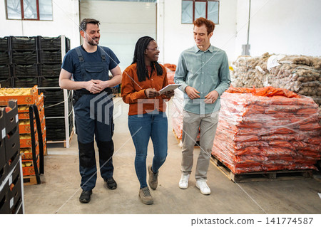 Diverse workers discussing logistics in produce warehouse with digital tablet Diverse workers discussing logistics in produce warehouse with digital tablet 141774587