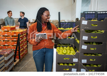 Female worker checking apple inventory in warehouse with tablet Female worker checking apple inventory in warehouse with tablet 141774594