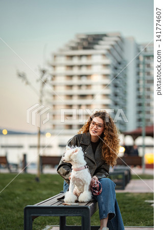 Woman with small dog sitting on park bench Woman with small dog sitting on park bench 141774607