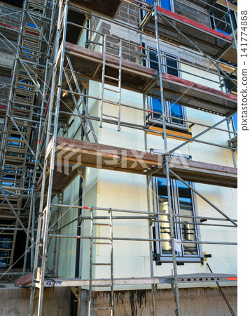 Scaffolding and Exterior Wall Insulation Installation on Modern Residential Building Under Construction Scaffolding and Exterior Wall Insulation Installation on Modern Residential Building Under Construction 141774868