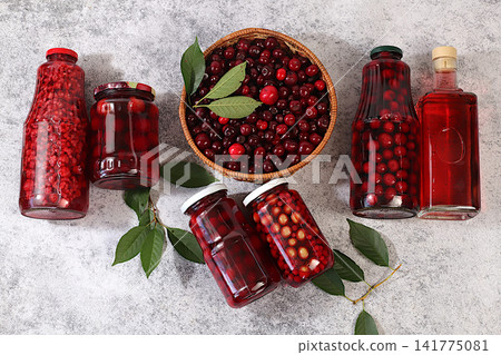 Cherry cider and berry compote on a concrete table, Thanksgiving decorations and a rustic harvest, healthy natural food and home canning concept, long-term storage at home, banner for a screen Cherry cider and berry compote on a concrete table, Thanksgiving decorations and a rustic harvest, healthy natural food and home canning concept, long-term storage at home, banner for a screen 141775081