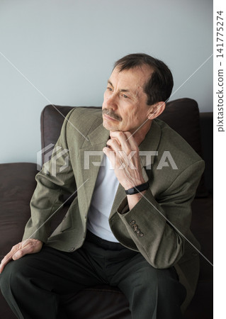 Caucasian Man Touching Chin, Thoughtful Expression And Focused Gaze Showing Reflective Mindset Retired Mentor Reviewing Life Chapters And Considering Creative Projects In Bright Natural Light Of Cozy Caucasian Man Touching Chin, Thoughtful Expression And Focused Gaze Showing Reflective Mindset Retired Mentor Reviewing Life Chapters And Considering Creative Projects In Bright Natural Light Of Cozy 141775274