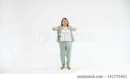 Middleaged Woman Doing Gentle Stretch In Sage Loungewear Against Neutral Studio Backdrop, Soft Lighting, Relaxed Expression, Focus On Posture And Breathing, Promoting Mobility And Self Care Middleaged Woman Doing Gentle Stretch In Sage Loungewear Against Neutral Studio Backdrop, Soft Lighting, Relaxed Expression, Focus On Posture And Breathing, Promoting Mobility And Self Care 141775401