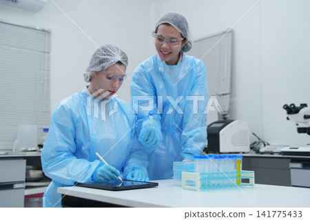 Laboratory Technicians Conducting Experiments with Test Tubes and Digital Device Laboratory Technicians Conducting Experiments with Test Tubes and Digital Device 141775433