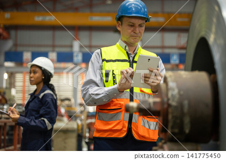 Quality Control Engineer Inspecting Large Industrial Steel Pipe Using Digital Tablet. Quality Control Engineer Inspecting Large Industrial Steel Pipe Using Digital Tablet. 141775450