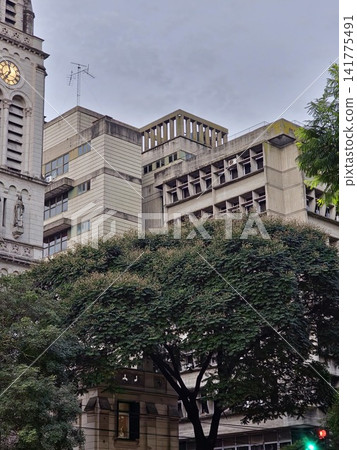 Buenos Aires, Argentina - March 28, 2026: Church Tower Partly Hidden by Trees and Modern Building Buenos Aires, Argentina - March 28, 2026: Church Tower Partly Hidden by Trees and Modern Building 141775491