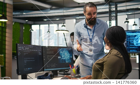 Pleased startup office manager applauding female programmer for optimizing code using AI. Satisfied team leader offering positive feedback to work done by IT specialist in office, camera A Pleased startup office manager applauding female programmer for optimizing code using AI. Satisfied team leader offering positive feedback to work done by IT specialist in office, camera A 141776360