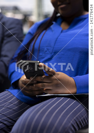 Checking flight information, smartphone close up and digital nomads in airport lobby. Doing business travel, mobile phone and freelancers checking flight schedule details, sitting on chairs Checking flight information, smartphone close up and digital nomads in airport lobby. Doing business travel, mobile phone and freelancers checking flight schedule details, sitting on chairs 141776434