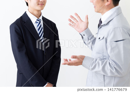 一位身穿西裝的年輕男子和一位身穿工作服的中年男子。 141776679