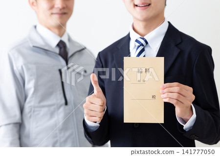 A young man in a business suit and a middle-aged man in work clothes are seen making a triumphant gesture while holding their pay envelopes. A young man in a business suit and a middle-aged man in work clothes are seen making a triumphant gesture while holding their pay envelopes. 141777050