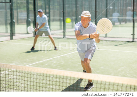 Elderly and adult men playing doubles padel 141777271