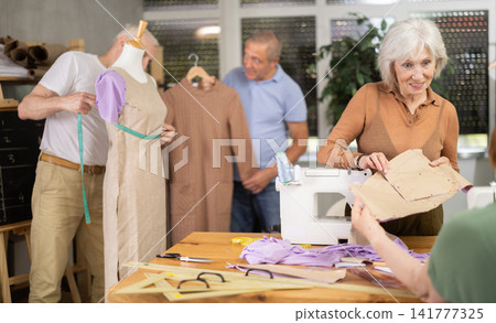Female teacher of tailoring course for seniors reviewing patterns with participant Female teacher of tailoring course for seniors reviewing patterns with participant 141777325