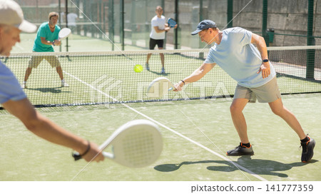 Men play padel on an outdoor tennis court. Hitting the ball with racket Men play padel on an outdoor tennis court. Hitting the ball with racket 141777359
