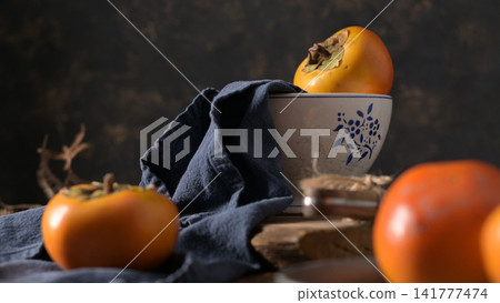 A rustic still life with fresh persimmons and a bowl A rustic still life with fresh persimmons and a bowl 141777474