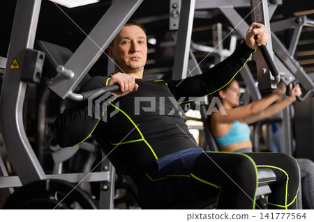 Adult man doing chest press on exercise machine in gym Adult man doing chest press on exercise machine in gym 141777564
