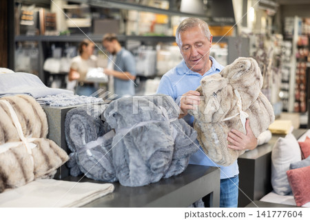 Elderly man choosing blanket in store Elderly man choosing blanket in store 141777604