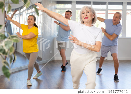 Woman participating in Zumba class for seniors in fitness studio Woman participating in Zumba class for seniors in fitness studio 141777641