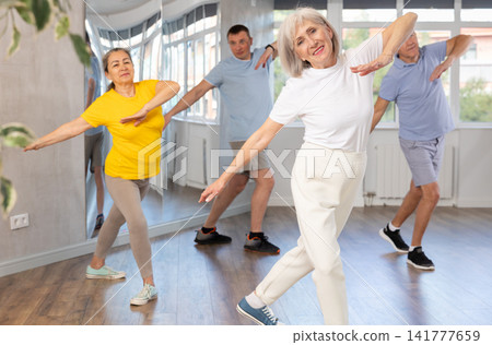 Woman participating in Zumba class for seniors in fitness studio Woman participating in Zumba class for seniors in fitness studio 141777659