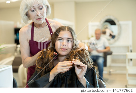 Professional hairdresser is doing fashionable haircut to young woman in hairdress salon Professional hairdresser is doing fashionable haircut to young woman in hairdress salon 141777661