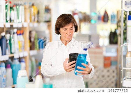 Elderly woman scanning qr code for cleaning spray Elderly woman scanning qr code for cleaning spray 141777715
