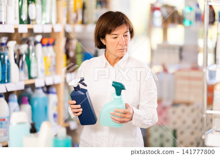 Elderly woman chooses cleaning spray in store Elderly woman chooses cleaning spray in store 141777800