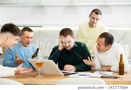 Men drink beer and try to help friend solve problems using laptop and Internet Men drink beer and try to help friend solve problems using laptop and Internet 141777864