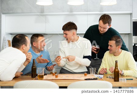 Cheerful men playing drinking board game at bachelor gathering Cheerful men playing drinking board game at bachelor gathering 141777886