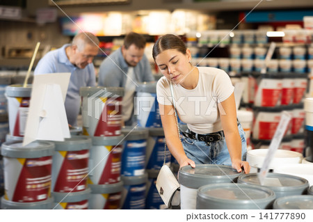 Young woman choosing paint in building store 141777890
