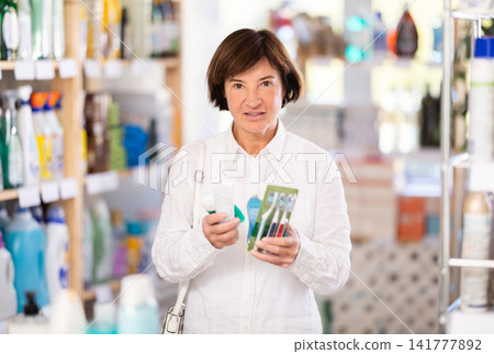 Woman shopper chooses dental kit - toothbrush and toothpaste in supermarket Woman shopper chooses dental kit - toothbrush and toothpaste in supermarket 141777892