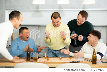 Friends drinking beer and enthusiastically playing board game at home Friends drinking beer and enthusiastically playing board game at home 141777922