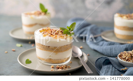 Layered dessert in glasses with cream and nuts Layered dessert in glasses with cream and nuts 141778000
