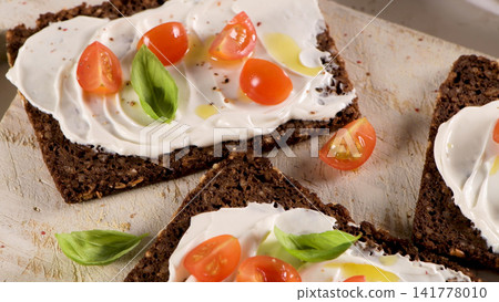 Dark rye bread toasts with cream cheese cherry tomatoes and basil Dark rye bread toasts with cream cheese cherry tomatoes and basil 141778010