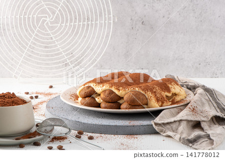 Traditional Italian tiramisu dessert dusted with cocoa powder on a white plate Traditional Italian tiramisu dessert dusted with cocoa powder on a white plate 141778012
