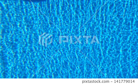 Rippled blue pool water surface reveals tiled floor pattern with sunlight caustic reflections Rippled blue pool water surface reveals tiled floor pattern with sunlight caustic reflections 141779014